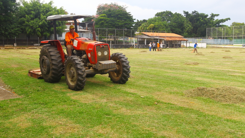 Máquina trabalha no corte de grama em campo de futebol 
